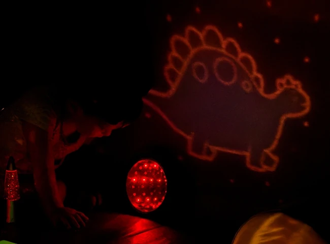 Image projetée d'un dinosaure sur le mur de l'espace snoezelen d'une crèche